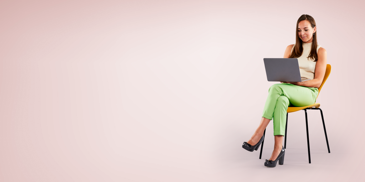 Woman sitting on wooden chair, with laptop on lap.