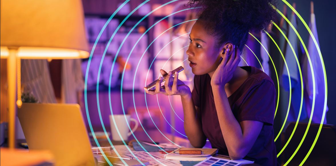 Women at desk holding phone openly and talking on loud speaker - surrounded by circular colours.