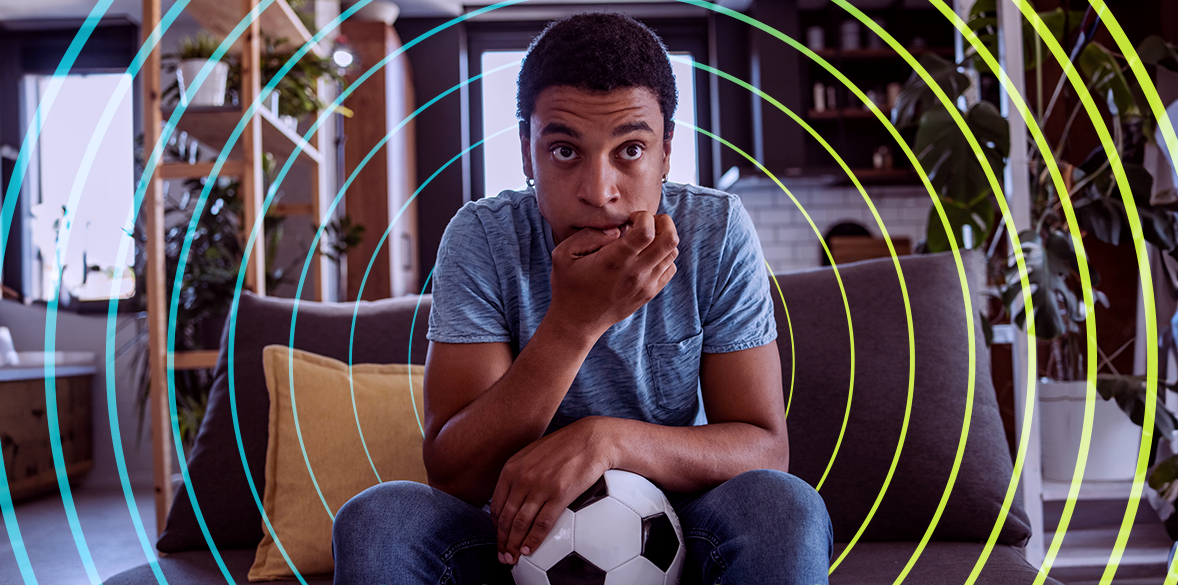 Man sitting on sofa watching football.