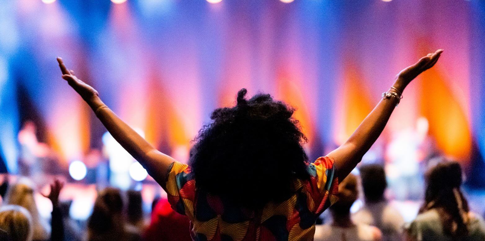 Women at concert with hands in the air in v shape